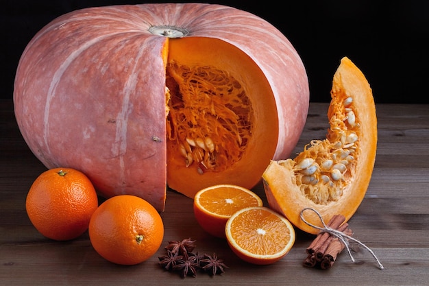 Mitades de naranja de calabaza orgánica entera fresca y palitos de canela sobre un fondo oscuro