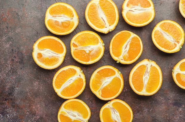 Mitades de naranjas sobre un fondo marrón oscuro.