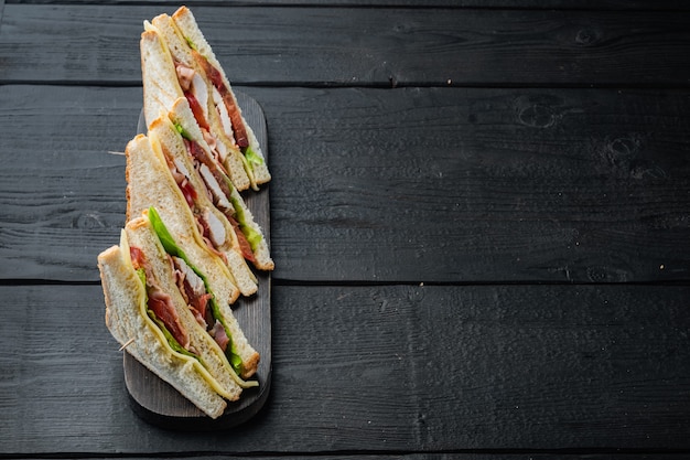 Foto mitades de sándwich de pollo casero, sobre mesa de madera negra con espacio para copiar texto