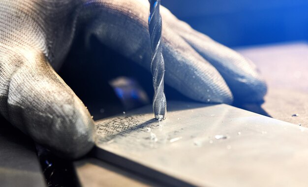 Mitarbeiter bohren Aluminiumflachstahlplatte mit Tischbohrmaschine Metallbohrer macht Löcher in Stahlknüppel auf Industriemaschine Metallbearbeitungsindustrie Nahaufnahme
