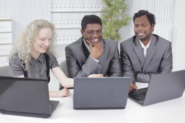 Mitarbeiter, die auf einen Laptop-Monitor schauen, sitzen am Tisch