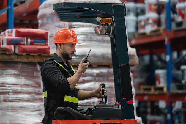 Mitarbeiter eines Managers oder Ingenieurs verwenden Walkietalkie, um dem Kollegen Befehle zu erteilen und den Lagerbestand auf dem Gabelstapler zu überprüfen