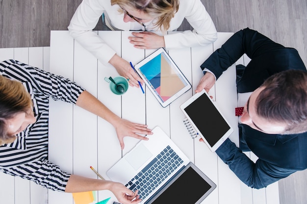 Mitarbeiter im Chat und mit Gadgets am Tisch