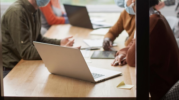 Mitarbeiter in Schutzmasken arbeiten in der Halle des Coworking