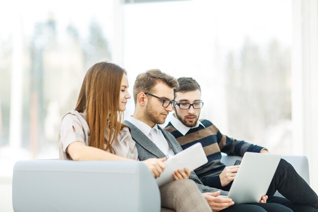 Mitarbeiter mit Laptop sitzen in der Lobby des Büros.