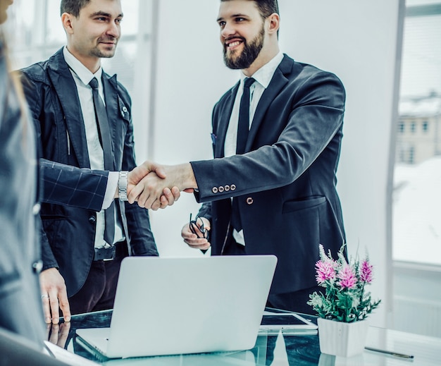 Mitglieder des Business-Teams und Handschlag des Managers und des Kunden vor Vertragsabschluss in einem modernen Büro.