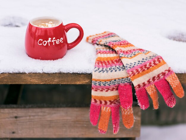 Mitones de punto multicolores y una taza roja con café