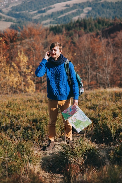 Mitreisender mit Karte in der Hand und Telefon. Herbstberge