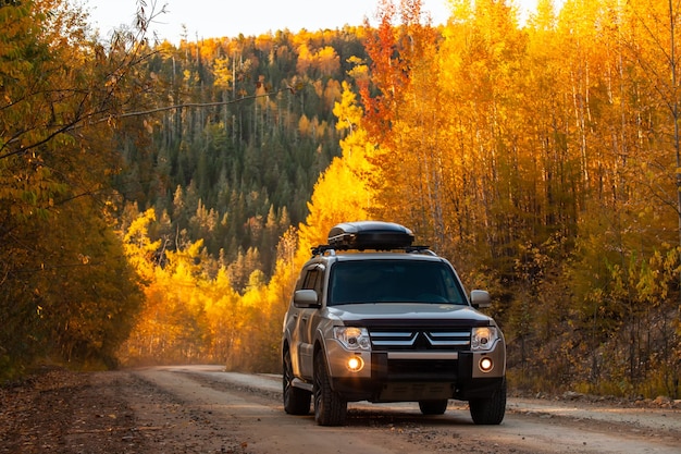 Mitsubishi Pajero en la pintoresca carretera de otoño en un hermoso bosque