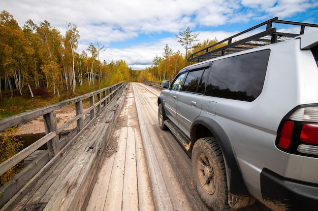 Mitsubishi Pajero Sport sobre puente de madera en el bosque de otoño