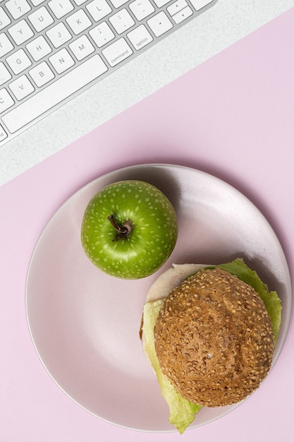 Mittagessen am Arbeitsplatz gesundes Sandwich nahe Laptop auf Arbeitstisch. Hauptnahrungsmittel für Bürokonzept