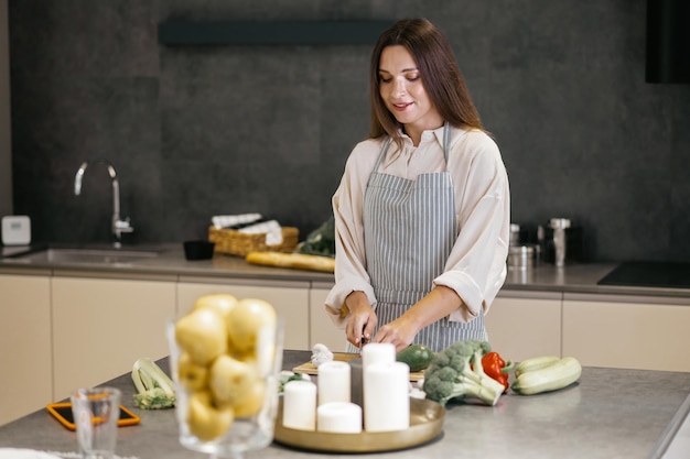 Mittagessen fertig machen. Junge Frau in Schürze schneidet Gemüse in der Küche