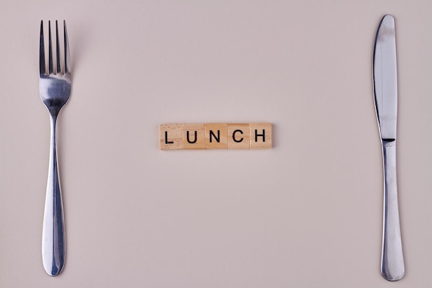 Mittagessen Inschrift aus Holzblöcken Gabel und Messer auf weißem Hintergrund