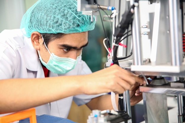 Mitte erwachsener männlicher Ingenieur, der Maschinenteil auf einer Produktionslinie in einer Fabrik untersucht.