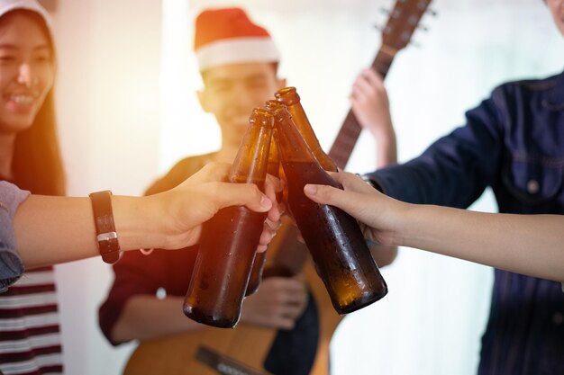 Foto mitte von freunden, die während einer weihnachtsfeier bierflaschen toasten