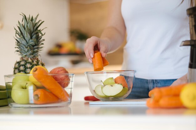 Mittel ausgewählte Weibchen legen geschnittene Äpfel und Karotten in Glasschüsseln frisches Obst und Gemüse