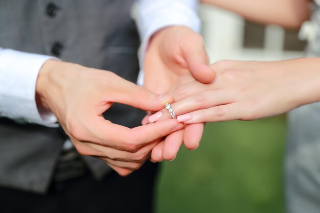 Foto mittelabschnitt des bräutigams, der den ring in den brautfinger steckt