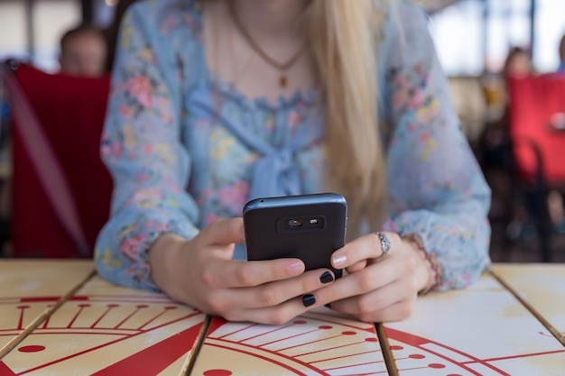 Foto mittelabschnitt einer frau, die am tisch ein handy benutzt