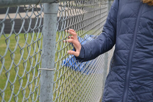 Foto mittelabschnitt einer frau, die an einem zaun mit kettenbändern steht