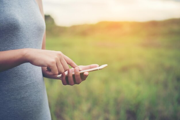 Mittelabschnitt einer Frau, die auf dem Feld steht und ein Telefon benutzt