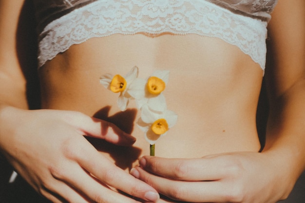 Mittelabschnitt einer Frau, die Blumen im Freien hält