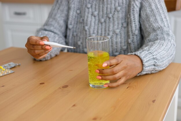Mittelabschnitt einer Frau, die ein Glas auf dem Tisch trinkt