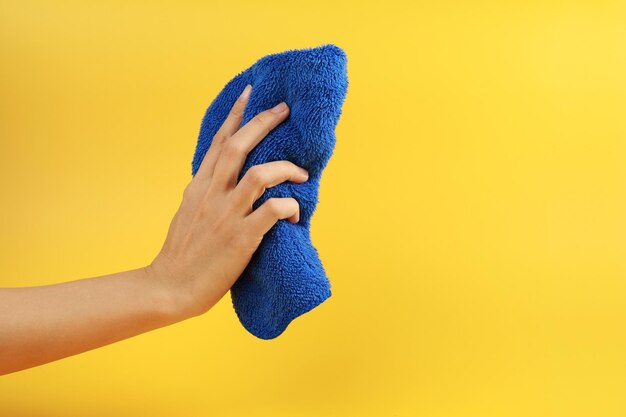 Foto mittelabschnitt einer frau, die eine gelbe blume vor grauem hintergrund hält