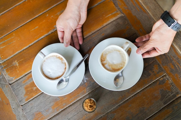 Foto mittelabschnitt einer frau, die eine kaffeetasse auf dem tisch hält