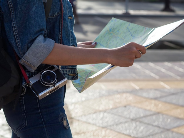 Mittelabschnitt einer Frau, die eine Karte auf einem Fußweg hält