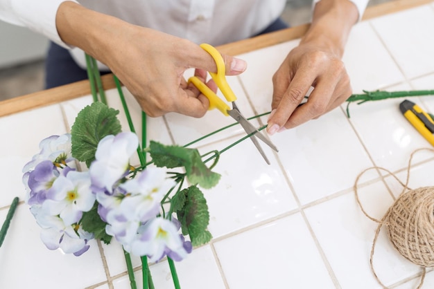 Mittelabschnitt einer Frau, die einen Blumenstrauß am Tisch herstellt