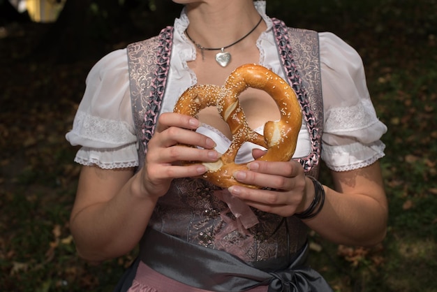 Mittelabschnitt einer Frau, die einen Brezel auf dem Feld hält