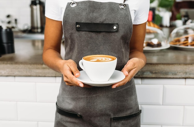 Mittelabschnitt einer Frau, die im Restaurant eine Kaffeetasse hält