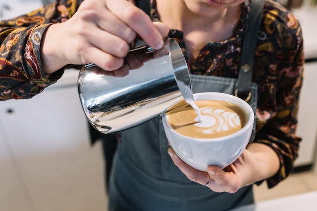 Mittelabschnitt einer Frau, die Kaffee in eine Tasse gießt