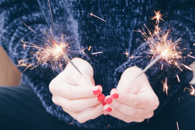 Mittelabschnitt einer Frau, die nachts ein Funkenblitz in der Hand hält