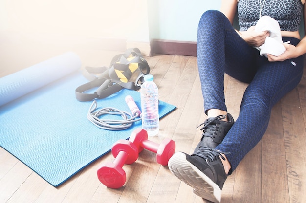 Mittelabschnitt einer Frau, die neben Sportgeräten sitzt