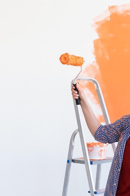 Mittelabschnitt einer Frau, die Orange vor weißem Hintergrund hält