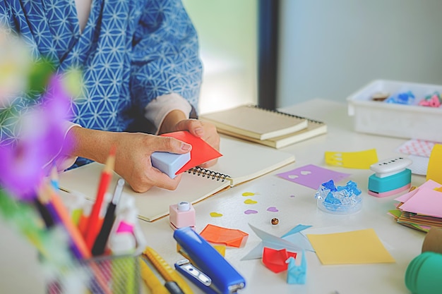 Mittelabschnitt einer Frau, die Papierhandwerk auf einem Schreibtisch macht
