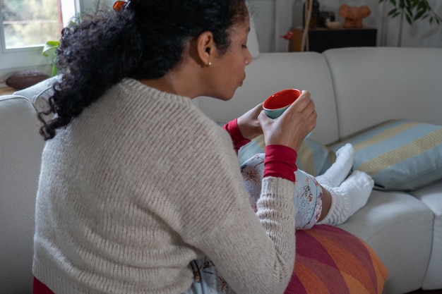 Mittelabschnitt einer Frau, die zu Hause auf dem Sofa sitzt