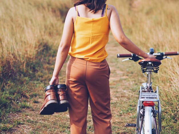 Foto mittelabschnitt einer frau mit fahrrad, die auf dem feld steht