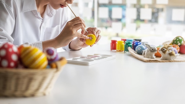 Mittelabschnitt einer jungen Frau, die Ostereier auf den Tisch malt