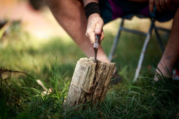 Foto mittelabschnitt einer person, die auf dem feld holz schneidet