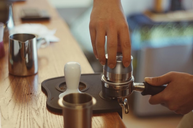 Foto mittelabschnitt einer person, die eine kaffeetasse auf dem tisch hält