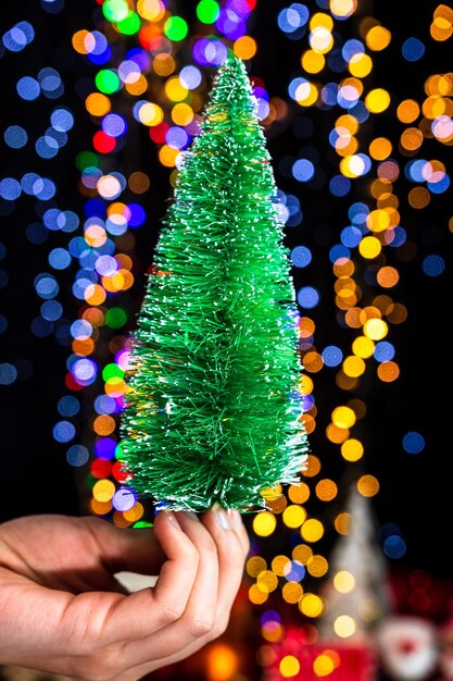 Foto mittelabschnitt einer person, die einen beleuchteten weihnachtsbaum hält