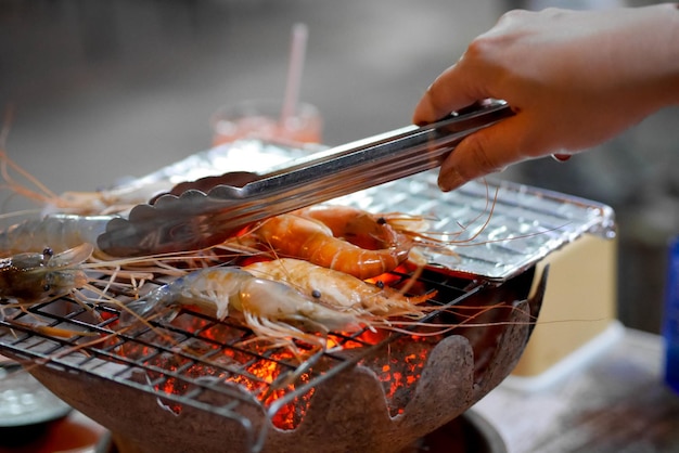 Foto mittelabschnitt einer person, die fleisch auf einem grill zubereitet