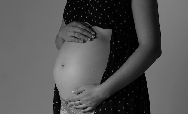 Mittelabschnitt einer schwangeren Frau, die den Bauch gegen die Wand berührt