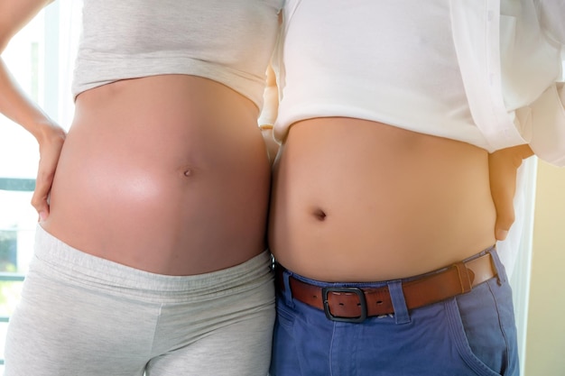 Foto mittelabschnitt einer schwangeren frau mit dem ehemann, der zu hause steht