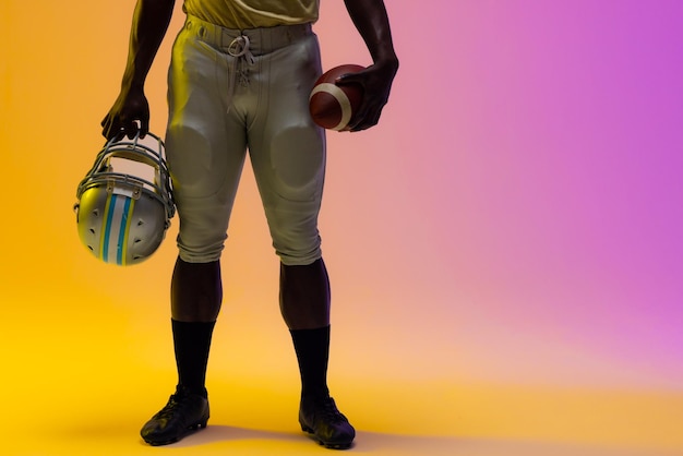 Foto mittelabschnitt eines afroamerikanischen männlichen american-football-spielers mit neonviolettem und gelbem beleuchtung