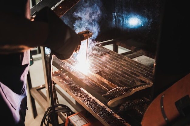 Foto mittelabschnitt eines arbeiters, der in einer werkstatt metall schweißt