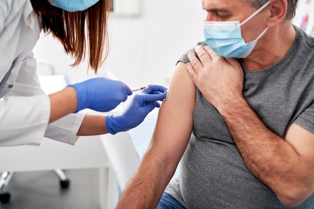 Mittelabschnitt eines Arztes, der dem Patienten eine Spritze injiziert