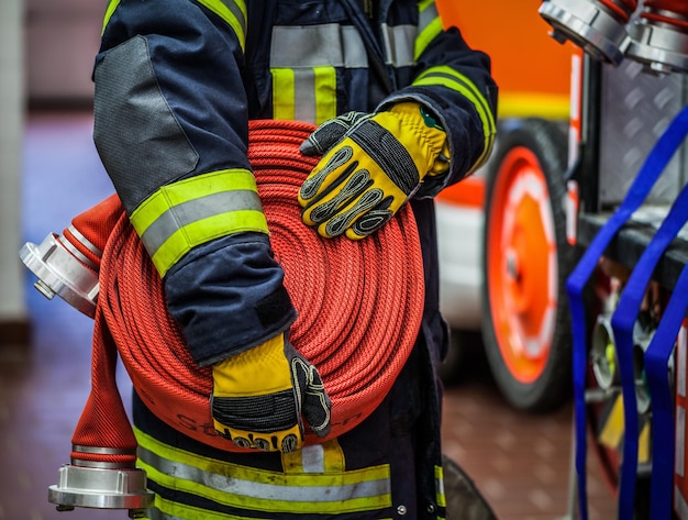 Mittelabschnitt eines Feuerwehrmanns, der einen Schlauch an einer Feuerwehrstation hält